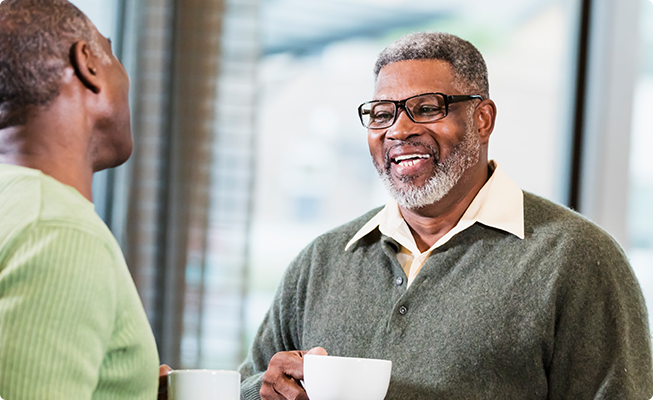 Men smiling while conversing over a cup of coffee